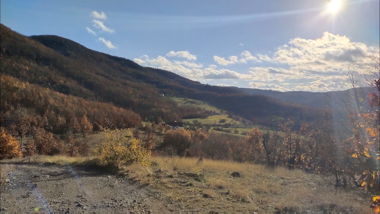 Staza na Radan planini sa pogledom na dolinu, šumu u jesenjim bojama i nekoliko kuća u podnožju brda