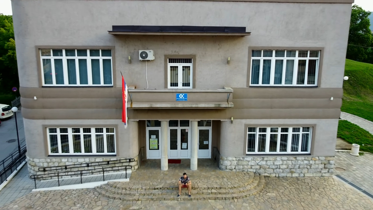 Zgrada u Prokuplju sa ulazom, stubovima i zastavom ispred, snimljena iz vazduha